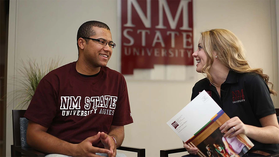 A student talks to a person in an NMSU polo shirt