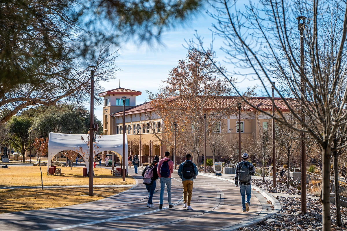 Individuals with backpacks walking on a campus path